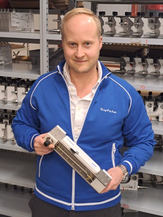 A young man holdiing a variable area flow meter in his hands. He looks straigt into the camera.